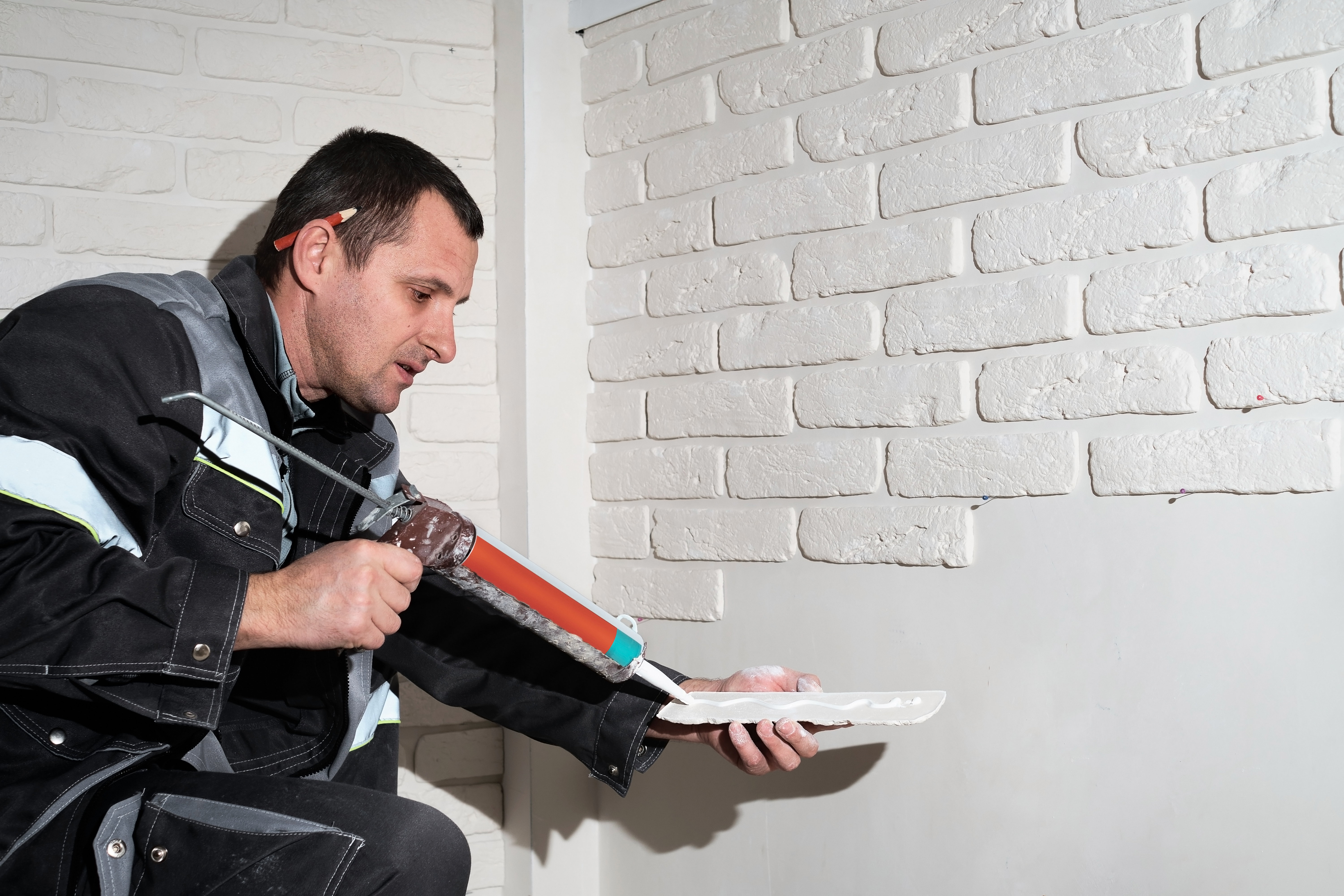 Master applies glue tiles for facing the house. The master builder decorates the walls of the apartment. Finishing the building with modern materials.